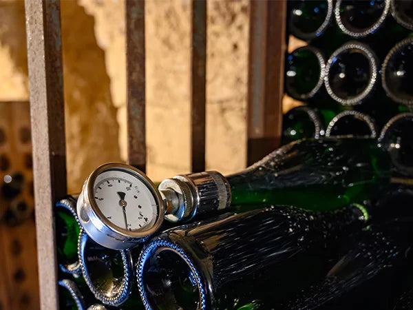 Einige Cremant Flaschen im Winzerkeller lagernd. Eine Flasche ist mit einem Druckmesser ausgestattet.